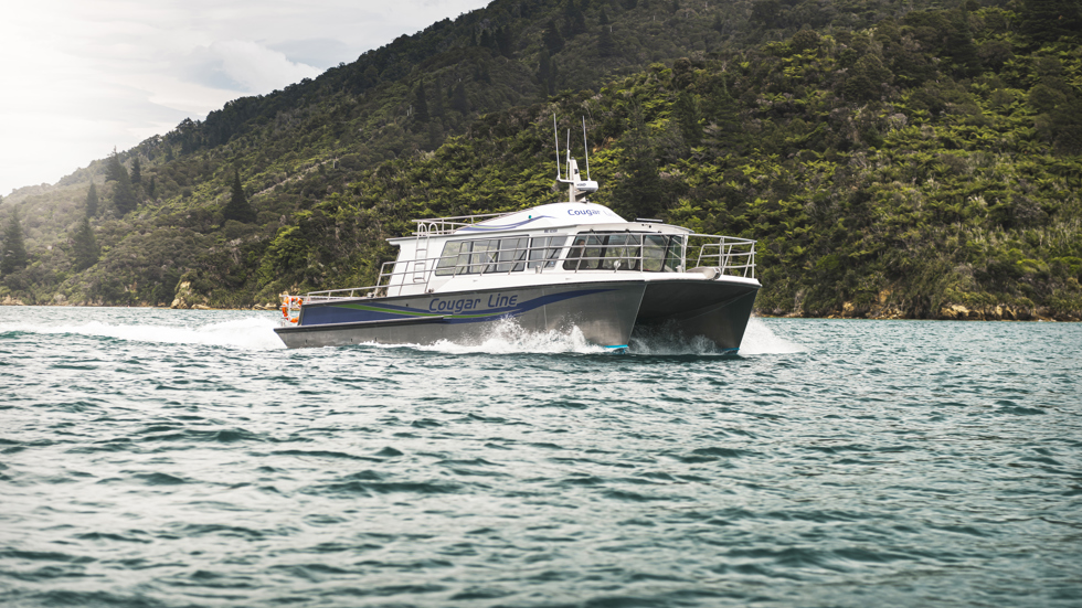 The name on the side of Cougar Line's Sounds Exciting boat sits above the boat's wake, while cruising the Marlborough Sounds, New Zealand