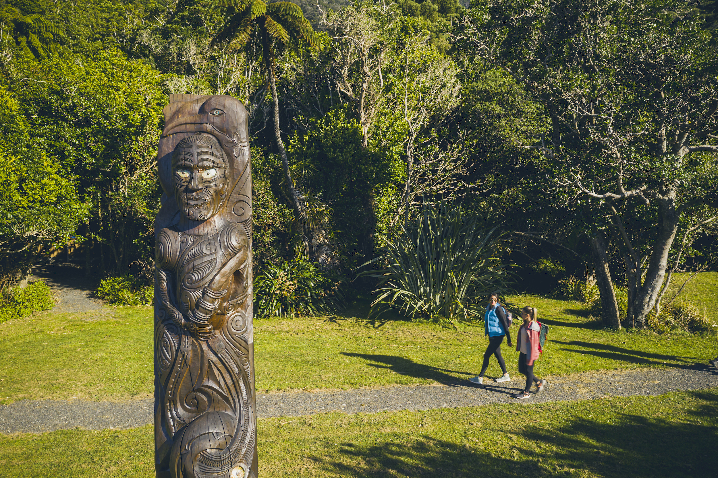 Two people walk at Ship Cove/Meretoto on the northern Queen Charlotte Track in the Marlborough Sounds, New Zealand.