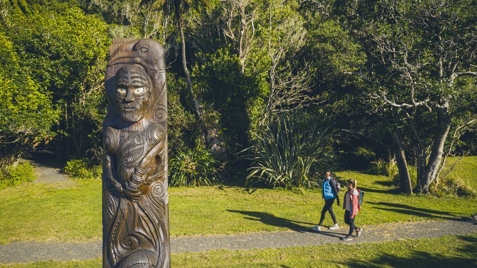 Two people walk at Ship Cove/Meretoto on the northern Queen Charlotte Track in the Marlborough Sounds, New Zealand.