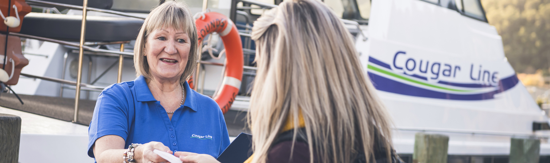 A passenger is greeted by a smiling Cougar Line staff member while boarding in Picton in the Marlborough Sounds, New Zealand.