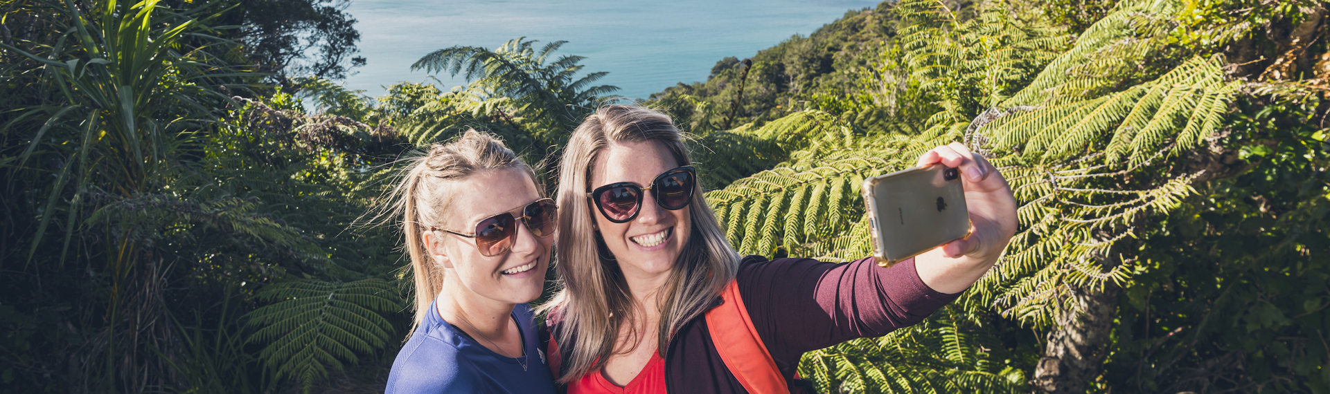 Two women take a selfie at a viewpoint on the northern Queen Charlotte Track in the Marlborough Sounds, New Zealand.