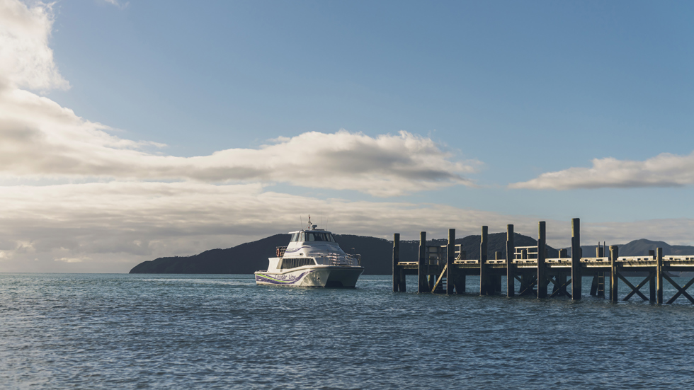 A Cougar Line boat approaches the jetty at Ship Cove/Meretoto at the start of the Queen Charlotte Track in outer Queen Charlotte Sound/Tōtaranui in the Marlborough Sounds, New Zealand..