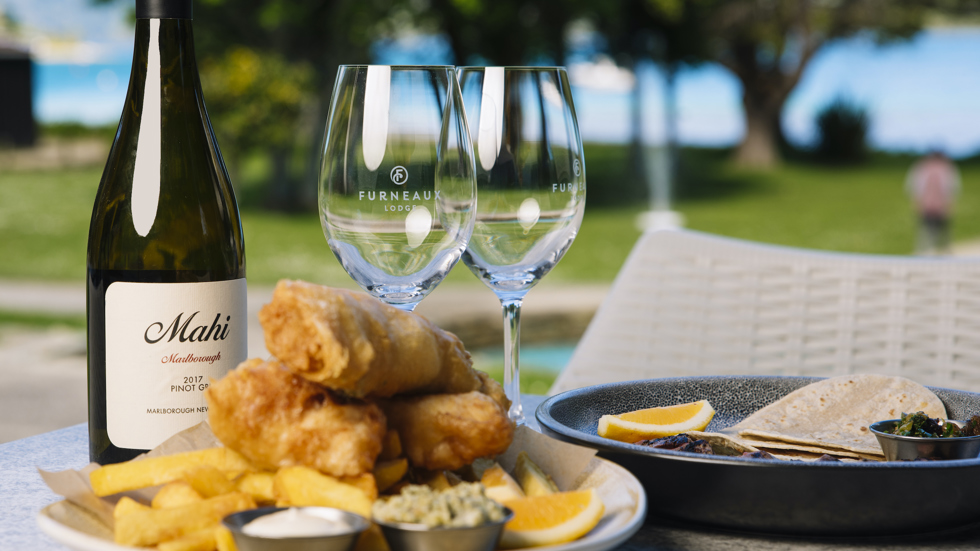 A plate of fish and chips and wine served at Furneaux Lodge in the Marlborough Sounds, New Zealand.