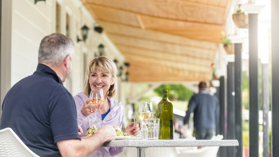 A couple dines at a table on the verandah at Furneaux Lodge in the Marlborough Sounds, New Zealand.