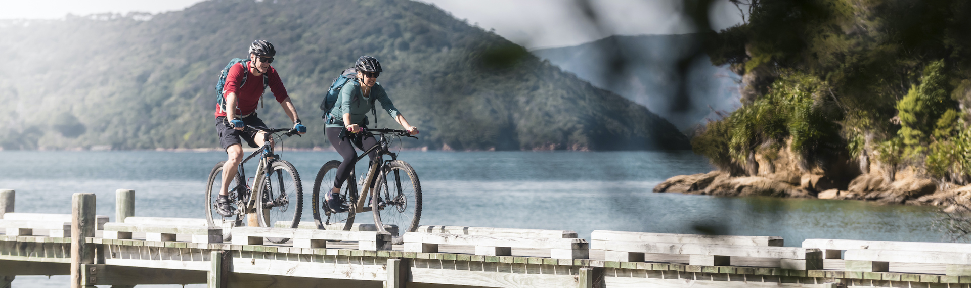 Two mountain bikers on the jetty at Ship Cove/Meretoto, about to start the Queen Charlotte Track in the Marlborough Sounds, New Zealand.